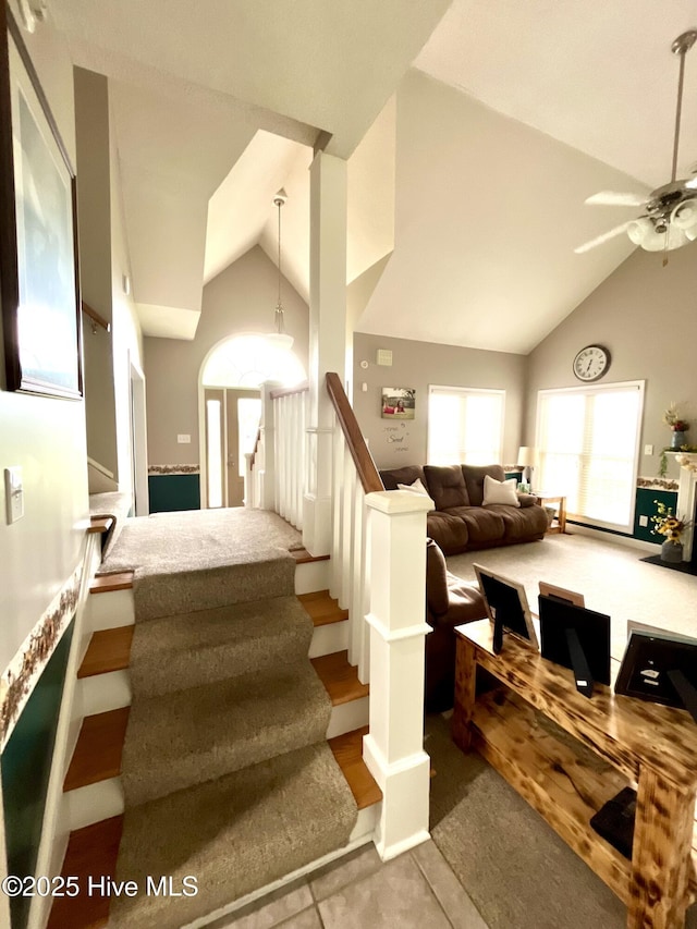 stairway with high vaulted ceiling, ceiling fan, and tile patterned floors