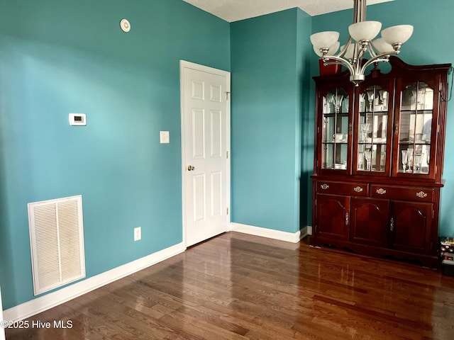 unfurnished dining area featuring a chandelier, wood finished floors, and baseboards