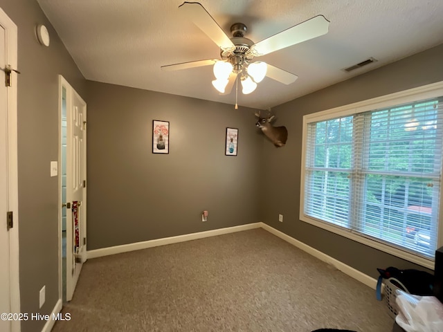 unfurnished room featuring a ceiling fan, carpet, baseboards, and a smoke detector