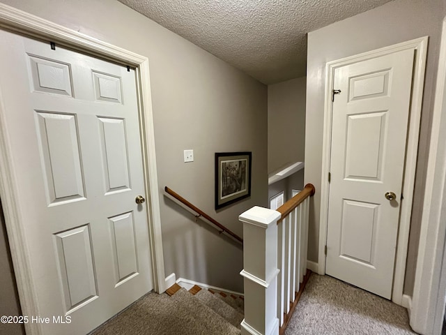 stairway with carpet flooring, a textured ceiling, and baseboards