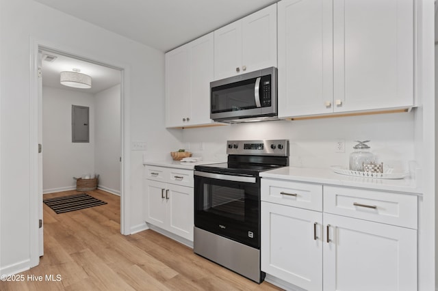 kitchen with appliances with stainless steel finishes, light countertops, light wood-style floors, and white cabinets