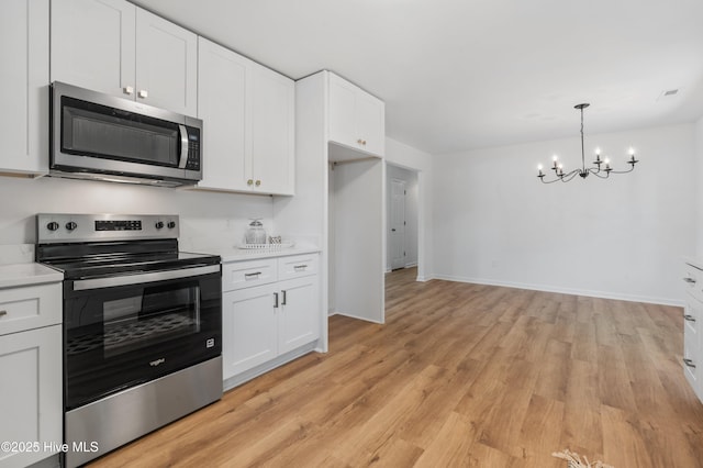 kitchen with appliances with stainless steel finishes, a chandelier, light countertops, white cabinetry, and light wood-style flooring