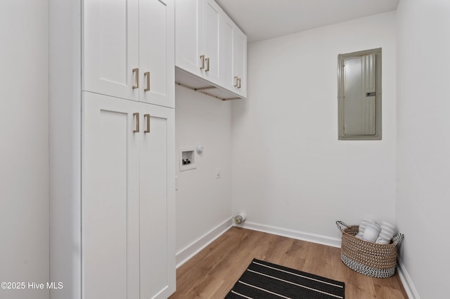 clothes washing area with cabinet space, electric panel, light wood-type flooring, baseboards, and washer hookup