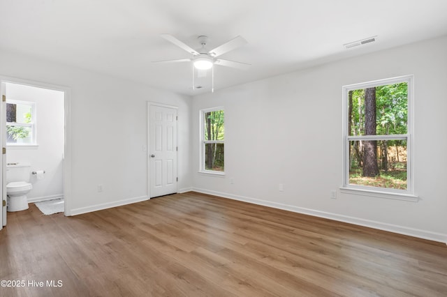 unfurnished bedroom with light wood-style flooring, baseboards, ensuite bath, and a ceiling fan