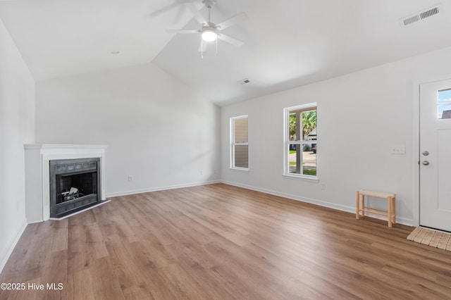 unfurnished living room with vaulted ceiling, ceiling fan, light wood-type flooring, a fireplace, and baseboards