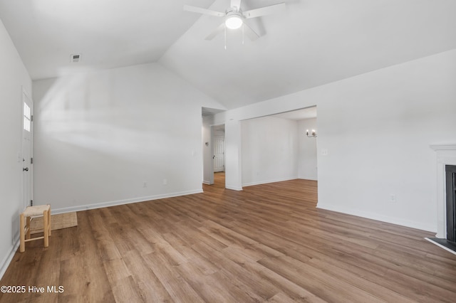 unfurnished living room with vaulted ceiling, light wood-type flooring, ceiling fan, a chandelier, and a fireplace