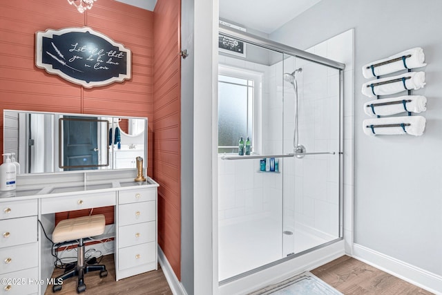 full bathroom with a shower stall, wood finished floors, baseboards, and vanity