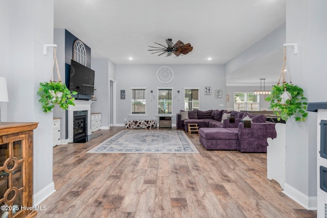 living area with a fireplace, a ceiling fan, wood finished floors, recessed lighting, and baseboards