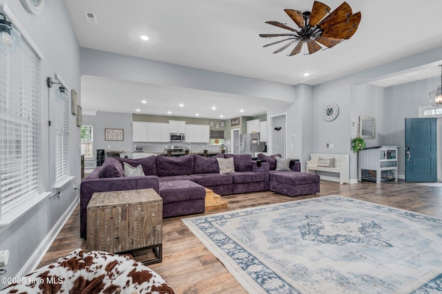 living room featuring light wood finished floors, a ceiling fan, recessed lighting, and baseboards