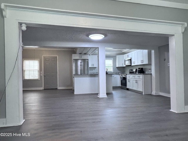 kitchen featuring appliances with stainless steel finishes, white cabinets, dark wood finished floors, baseboards, and open floor plan
