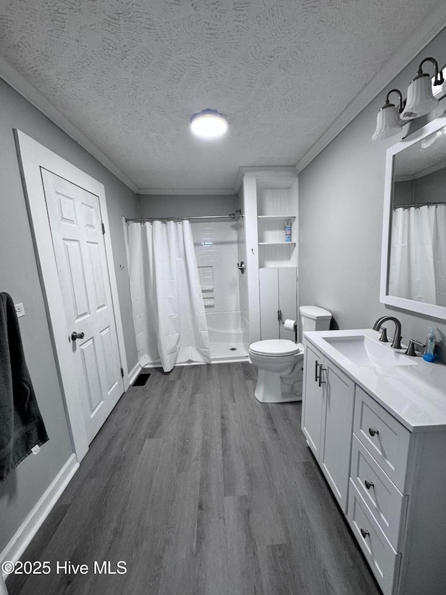 bathroom with wood finished floors, curtained shower, toilet, a textured ceiling, and vanity