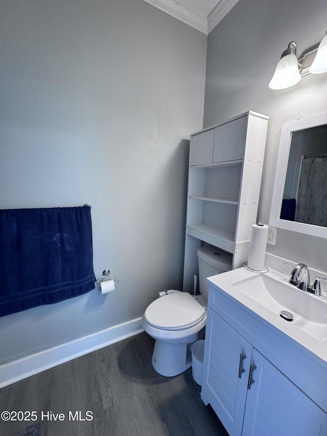 bathroom with ornamental molding, wood finished floors, toilet, vanity, and baseboards