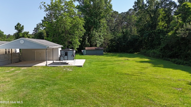 view of green lawn featuring a carport and a patio area