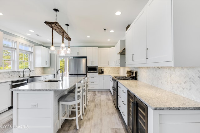 201 W Yacht Dr, Oak Island, NC 28465 - kitchen featuring appliances with stainless steel finishes, a sink, beverage cooler, white cabinetry, and backsplash