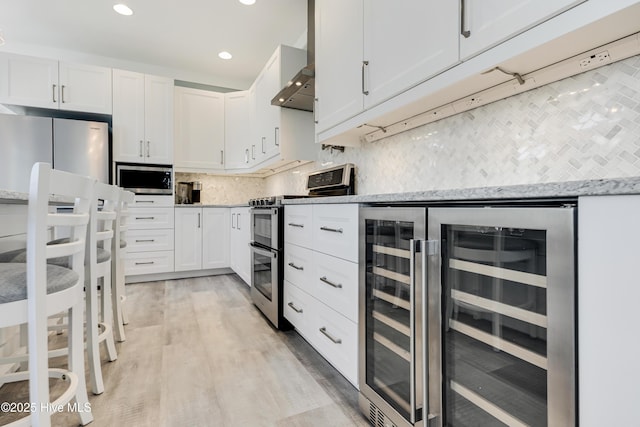 201 W Yacht Dr, Oak Island, NC 28465 - kitchen featuring beverage cooler, stainless steel appliances, decorative backsplash, white cabinetry, and light wood finished floors