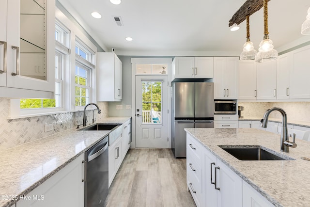201 W Yacht Dr, Oak Island, NC 28465 - kitchen featuring appliances with stainless steel finishes, a sink, white cabinetry, tasteful backsplash, and recessed lighting