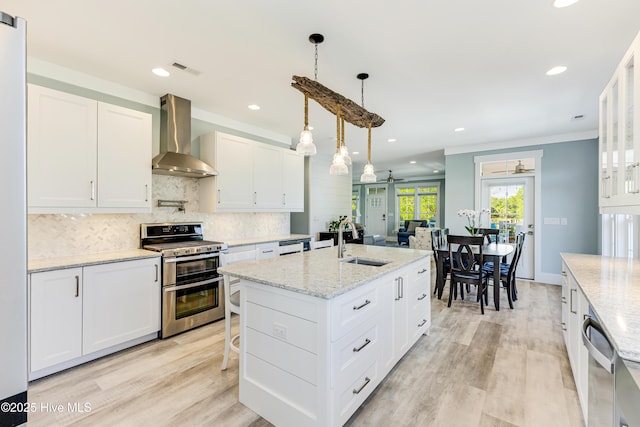 201 W Yacht Dr, Oak Island, NC 28465 - kitchen with stainless steel appliances, wall chimney exhaust hood, a sink, backsplash, and light wood-style floors