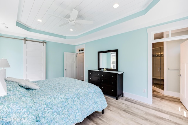 201 W Yacht Dr, Oak Island, NC 28465 - bedroom featuring a barn door, light wood-style floors, a raised ceiling, recessed lighting, and baseboards