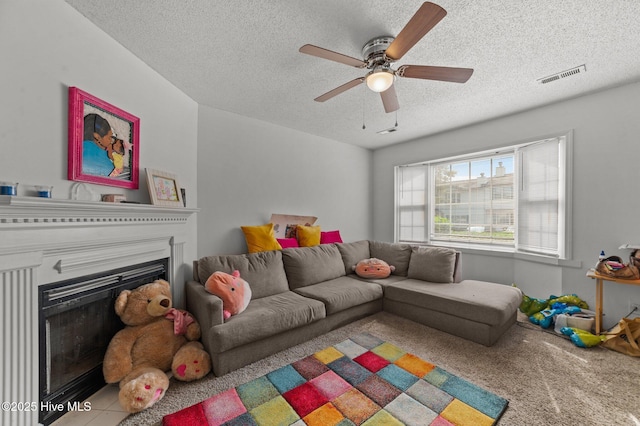 living area with a textured ceiling, a fireplace, a ceiling fan, and carpet flooring
