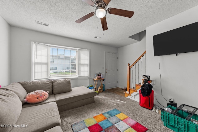living room featuring stairway, a ceiling fan, carpet floors, and a textured ceiling