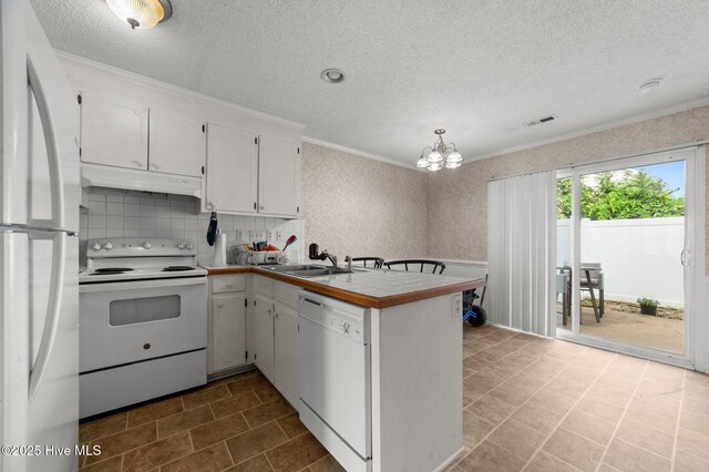 kitchen featuring white appliances, under cabinet range hood, a sink, a peninsula, and a textured ceiling