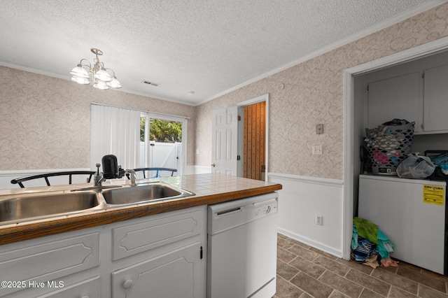kitchen featuring white dishwasher, crown molding, wallpapered walls, a sink, and a textured ceiling