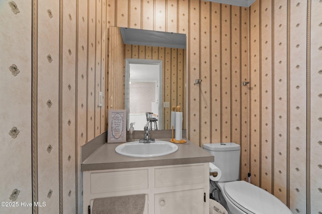 bathroom featuring wallpapered walls, toilet, vanity, and ornamental molding