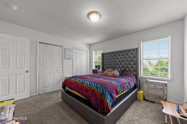 carpeted bedroom featuring multiple closets and a textured ceiling