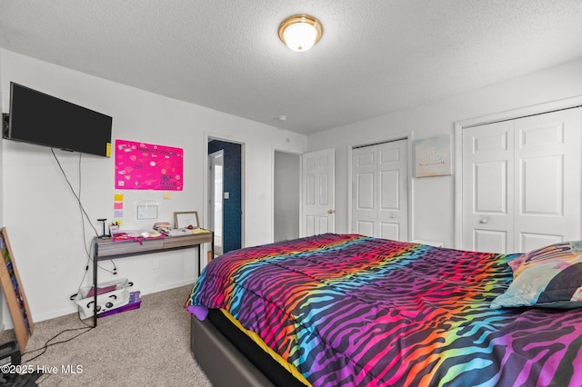 carpeted bedroom featuring two closets, a textured ceiling, and baseboards