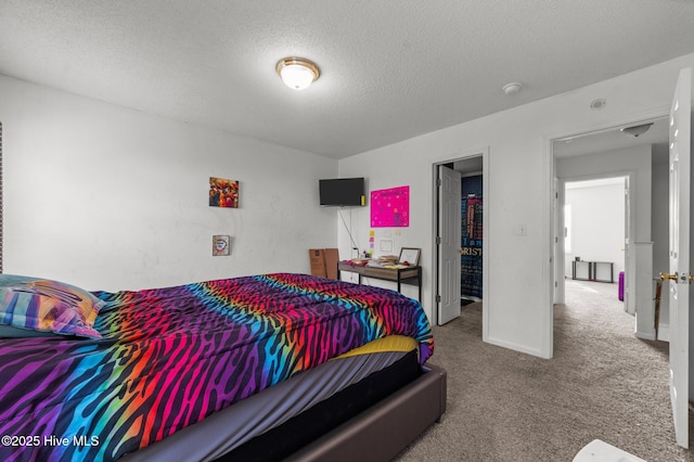 carpeted bedroom featuring a textured ceiling and baseboards