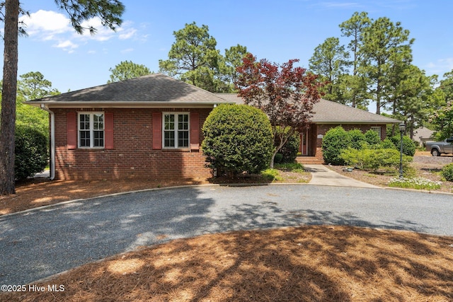 bungalow featuring brick siding and a shingled roof