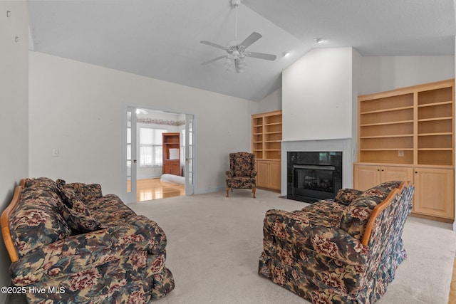 living room featuring lofted ceiling, a high end fireplace, carpet, and a ceiling fan