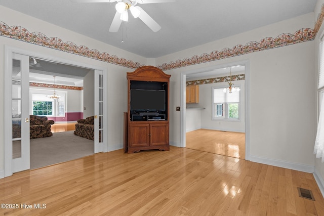 empty room featuring a chandelier, light wood-style floors, and healthy amount of natural light