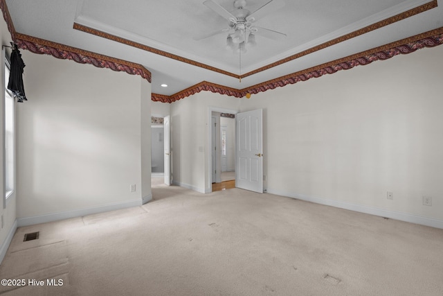 unfurnished bedroom featuring a tray ceiling, light colored carpet, baseboards, ornamental molding, and ensuite bathroom