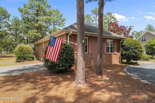 view of property exterior featuring brick siding and a shingled roof
