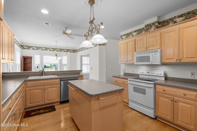 kitchen with white appliances, a sink, ceiling fan, light wood finished floors, and a textured ceiling
