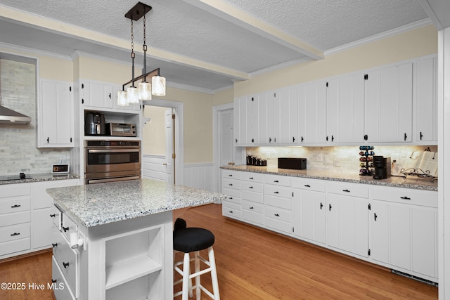2008 S Elm St, Greenville, NC 27858 - kitchen featuring a textured ceiling, stainless steel double oven, beamed ceiling, white cabinetry, and a wainscoted wall