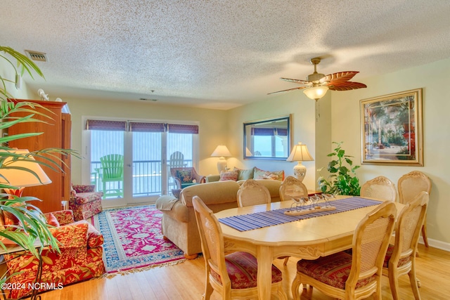 dining room with a textured ceiling, light wood-type flooring, and ceiling fan