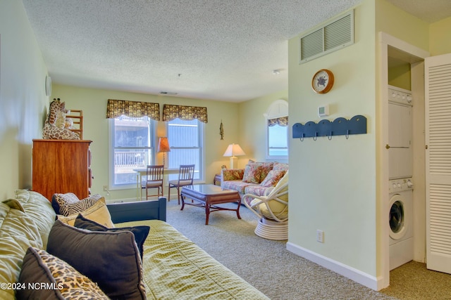 carpeted living room featuring estacked washer and dryer, a textured ceiling, and baseboards