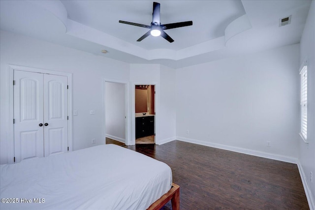 222 Station House Rd, New Bern, NC 28562 - bedroom featuring a tray ceiling, dark wood-style flooring, baseboards, a closet, and connected bathroom