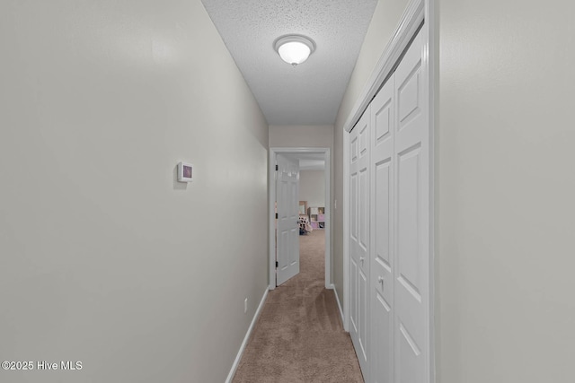 corridor with carpet floors, baseboards, and a textured ceiling