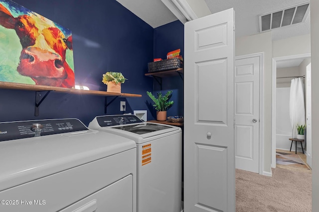 laundry area with washer and dryer and light colored carpet