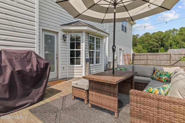view of patio featuring outdoor lounge area, fence, a wooden deck, outdoor dining area, and area for grilling