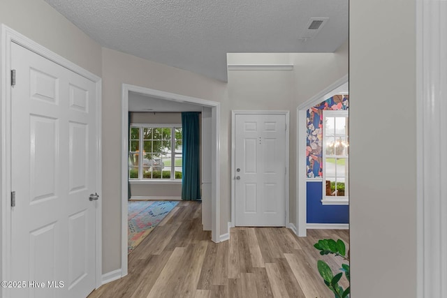 entrance foyer featuring baseboards, light wood finished floors, and a textured ceiling