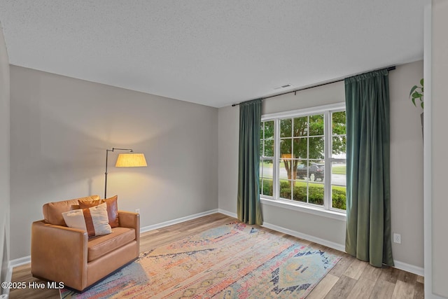 sitting room featuring wood finished floors, baseboards, and a textured ceiling