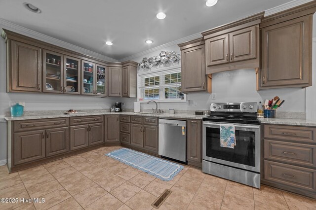 859 Old Pamlico Beach Rd W, Belhaven, NC 27810 - kitchen featuring appliances with stainless steel finishes, a sink, ornamental molding, glass insert cabinets, and light stone countertops