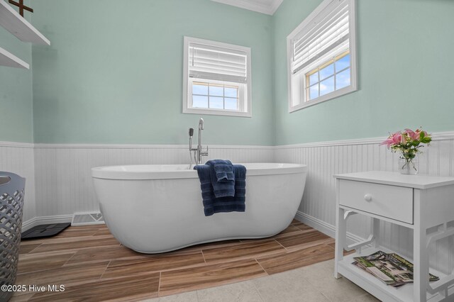 859 Old Pamlico Beach Rd W, Belhaven, NC 27810 - bathroom featuring wainscoting, wood finish floors, a freestanding tub, and ornamental molding