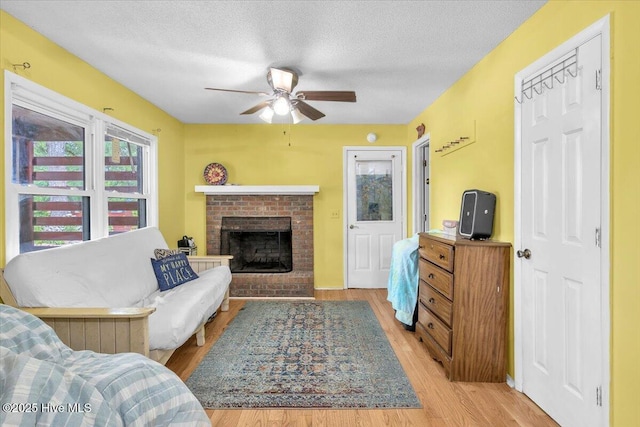 4407 E Oak Island Dr, Oak Island, NC 28465 - living room featuring a ceiling fan, light wood-style floors, a brick fireplace, and a textured ceiling