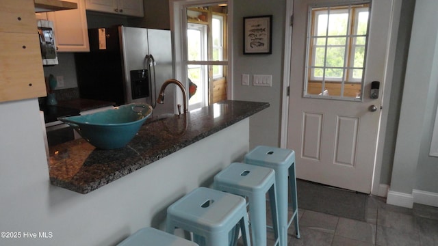 105 Sandy Landing Rd, Cedar Island, NC 28520 - kitchen with stainless steel fridge, a kitchen bar, light tile patterned floors, a sink, and baseboards