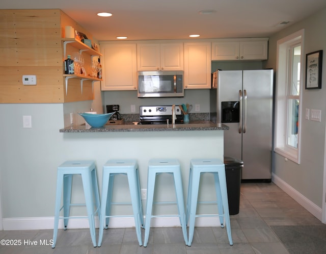 105 Sandy Landing Rd, Cedar Island, NC 28520 - kitchen featuring stainless steel appliances, a peninsula, a kitchen bar, baseboards, and white cabinetry
